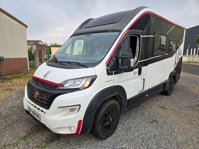 une photo d'un camping-car blanc et rouge garé sur le bord de la route