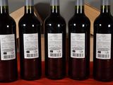four bottles of wine are lined up on a red table cloth
