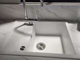 a white sink with a chrome faucet in front of a window