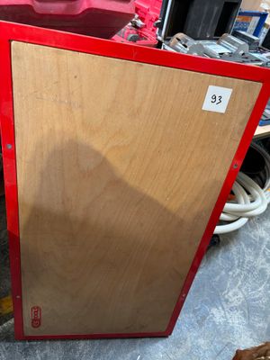 a red refrigerator sitting on the floor next to a red truck