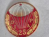 un pin's rouge et doré sur lequel est représenté un parachute