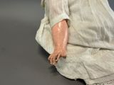 a doll that is sitting on the ground wearing a white dress