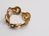 a close up of a gold bracelet on a white surface