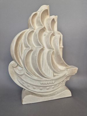 sculpture représentant un voilier sur un socle, sur fond gris