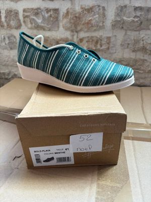 pair of blue and white striped shoes sitting on top of a cardboard box