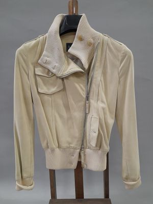 une photo d'une veste beige posée sur un portant en bois, sur fond gris