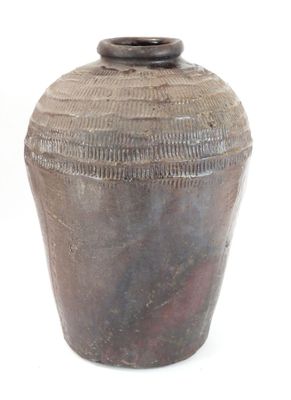 un vase brun posé sur une surface blanche