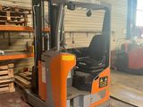 an orange and black forklift in a warehouse with pallets