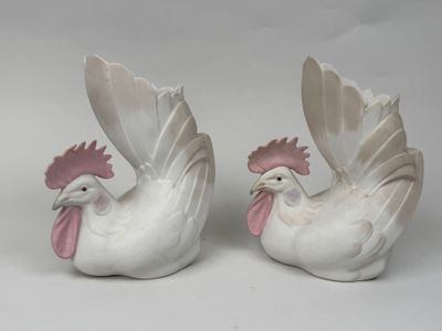 pair of white ceramic rooster figurines with pink beaks on white background