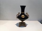 a black and gold vase sitting on a white table