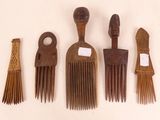 five wooden combs and a brush on a white surface