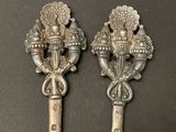 two silver spoons with handles and handles on a black surface