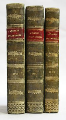 three old books sitting on top of each other on a white surface