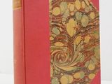 un vieux livre à la couverture rouge posé sur une table blanche