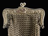 an old silver purse with chain around it on a black background