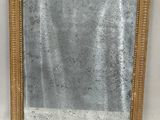 un miroir à cadre doré posé sur un mur blanc