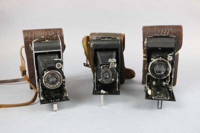 two old cameras are sitting side by side on a white surface