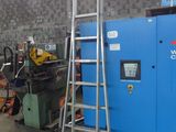une échelle appuyée contre un mur, à côté d'une machine bleue