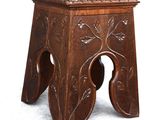 a small wooden stool with a carved design on it