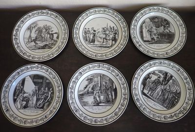 six black and white plates with pictures of people on them on a table