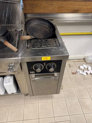 une cuisinière sur laquelle est posée une poêle, dans une cuisine