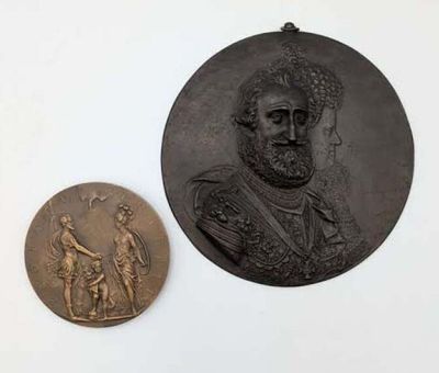 deux médaillons en bronze représentant un homme et une femme sur un fond blanc