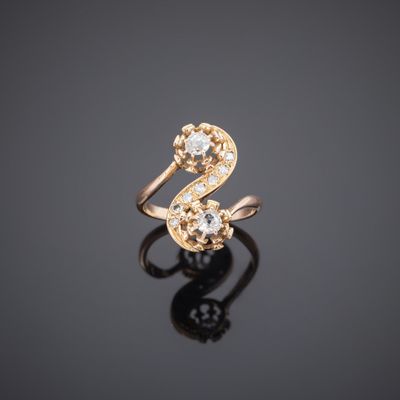 a gold ring with two diamonds on a black surface