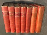 several red books are lined up on a shelf in a room