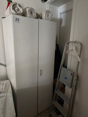 un réfrigérateur blanc dans un coin de la pièce, à côté d'une échelle