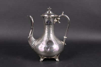 an antique silver tea pot with a bird handle on a black surface