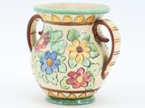 a small vase with flowers painted on it on a white surface