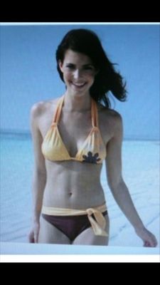 a woman in a yellow bikini standing on the beach