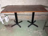 a table with two black legs and a brown table top