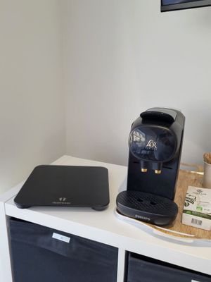 a coffee maker on a white shelf next to a tv