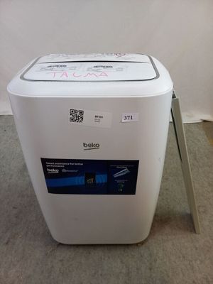 une petite machine à laver posée par terre dans une pièce