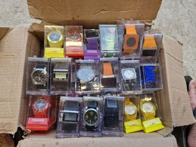 une boîte remplie de montres de toutes sortes posée par terre
