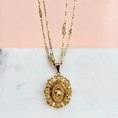 a close up of a necklace on a marble surface with a pink background