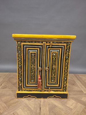 a black and gold painted cabinet on a wooden floor