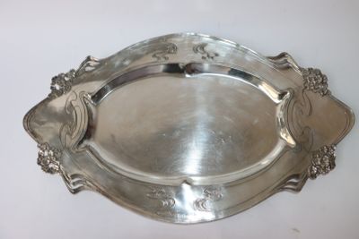 un plateau en argent muni d'une poignée, posé sur une table blanche