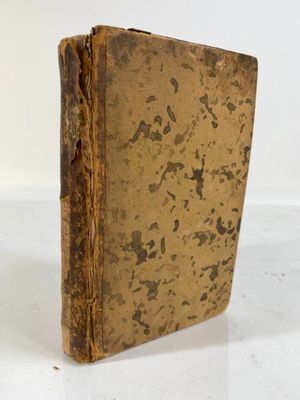 un vieux livre posé sur une table blanche à côté d'un mur blanc