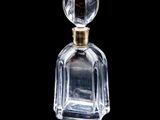 flacon de parfum en verre transparent avec un bouchon doré, sur fond noir