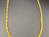 a gold necklace with a braid design on a black background