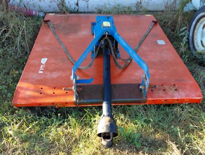 a blue and orange plow sitting in the grass