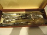 des couverts dans un coffret en bois posé sur une table avec un fond jaune