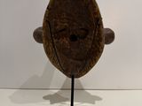 an image of a wooden mask on a stand on a white surface