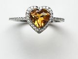 un gros plan d'une bague en forme de cœur sertie de diamants, sur fond blanc