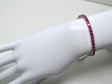 une main de mannequin blanche à laquelle est attaché un bracelet rouge
