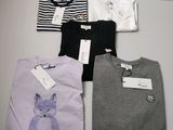 Quatre t-shirts avec un chat dessus sont posés sur une table