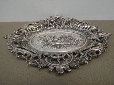 une assiette en argent finement décorée, sur laquelle figure l'image d'un cheval et de son cavalier