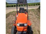 an orange tractor parked in a field on a cloudy day